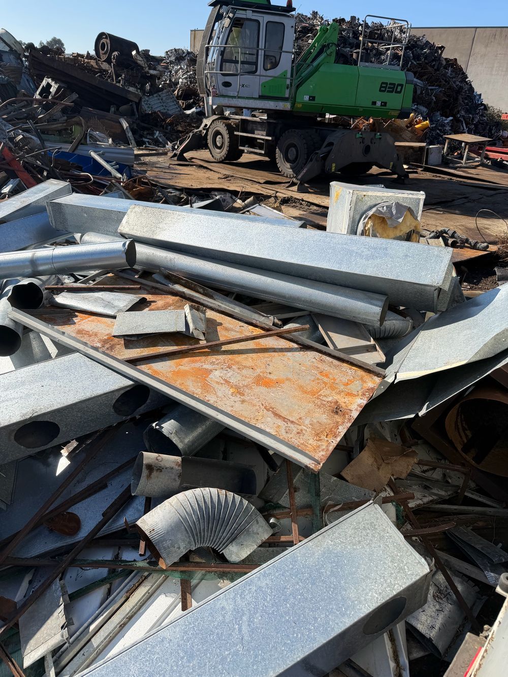 Scrap yard with steel ducting and an excavator for ferrous metal and equipment removals